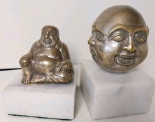 Buddha-Kopf mit vier Gesichtern und sitzender Buddha auf Marmorsockel.