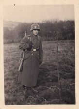 Foto - Soldat mit Stahlhelm und Mantel im Gelände - 2.WK