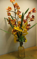 Amberfarbene Kristallkaraffe mit braun-gelben Orchideen und gelben Ginkoblätter 