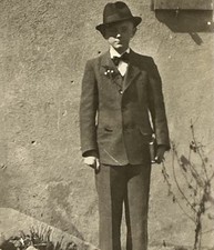 Junge steht im Anzug mit Hut