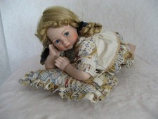 Liegendes Puppenkind aus Porzellan mit Kissen