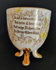Antike Porzellantasse mit Spruch auf drei goldenen Füßen