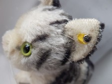 Katze Tabby Steiff mit Knopf und gelbem Fahnenrest im Ohr, bespielt.