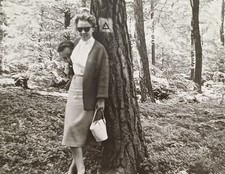 Elegante Frau steht in typische 60er Jahre Mode im Wald Mann versteckt sich Foto