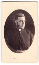 Fotografie Pfarrer im Talar mit Collar und Backenbart 