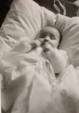 Süßes Baby Säugling Mädchen ballt die Fäuste liegt im Kissen Bett Altes Foto