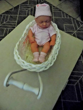 kleine Puppe mit Bekleidung in rosa im Puppenwagen