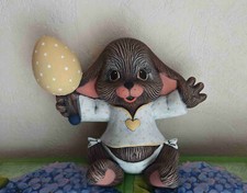 Oster-Dekoration Hasenbaby mit Rassel-Osterei in einer Hand