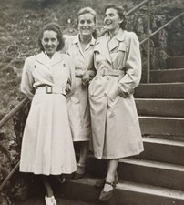Drei junge lachende Frauen stehen in Mänteln albern rum Freundinnen Treppe Foto