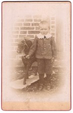Fotografie junger Knabe mit seinem Schaukelpferd auf Rollen 