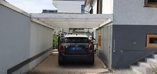 Carport aus UV-festen Doppelstegplatten und lackierten Holzbalken