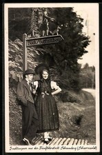 AK Schramberg /Schwarzwald, Trachtenpaar aus der Fünftälerstadt an einem Wegwei 