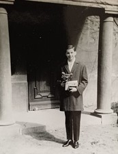 Junge steht stolz mit Blumen Buch vor Portal Kirche Säulen Konfirmation Foto
