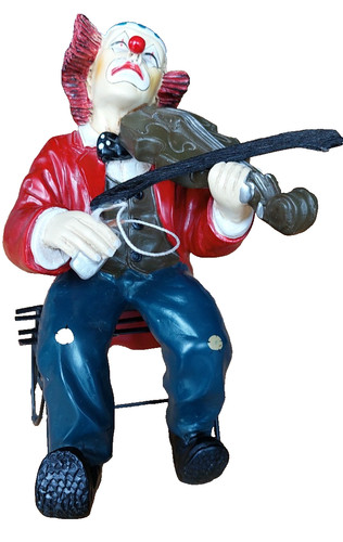 Clownfigur sitzend mit - , geige