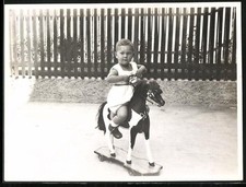 Fotografie kleines Kind auf seinem Schaukelpferd auf Rollen 