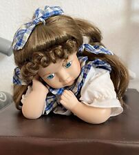 Süßes Püppchen liegend, mit langem Haar und Schleife, Oberteil und Hose kariert