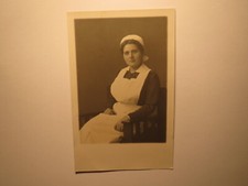 sitzende Frau in Schürze und Haube - Krankenschwester ? Bedienstete ? / Foto