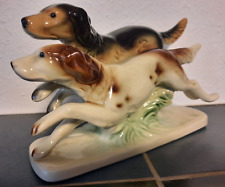 Dekorative Porzellanfigur:  Zwei rennende Jagdhunde auf Sockel.