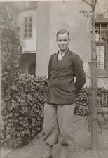 Frecher junger Mann steht lässig in Knickerbocker Hose im Garten Hinterhof Foto