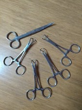 vier Tuchklemmen ( Backhausklemmen) und eine gebogene Schere