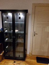 Schwartzer Vetrienenschrank Mit Viel Gllas Und Beleuchtung.