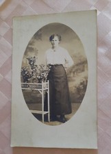 schönes ovales Damenporträt stehend an Blumenregal vor Leinwand als Postkarte