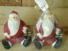 Kerze sitzender Weihnachtsmann mit Geschenk in Geschenkverpackung "A"