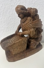 Alte geschnitzte Holzfigur einer Frau mit einem Kind beim Waschen. 