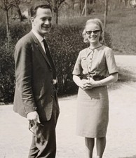 Paar steht lachend auf der Stra schöne Frau in 60er Jahre Mode Sonnenbrille Foto