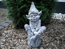 Steinfigur Troll auf Baumstamm
