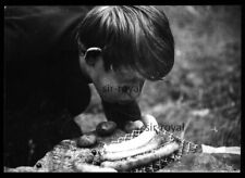 Junge mit Sommersprossen pustet ins Feuer am Grill mit Bratwurst - Foto 10x7cm