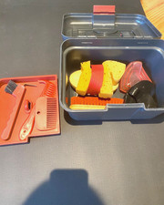 kleiner, schwarz/roter Putzkasten zusammen mit einem Putzset