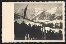 Foto-AK Skispringer beim Sprung vor Publikum und Gipfelpanorama 