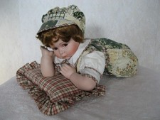 Liegendes Puppenkind aus Porzellan mit Kissen