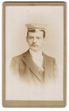 Fotografie junger Student im Anzug mit Schirmmütze und Moustache 