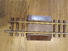 LGB Trenngleis mit braunem Bahnübergang. Beide Schienen werden unterbrochen.