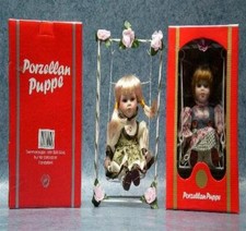 Porzellankopfpuppe auf Schaukel in grünem Kleid - Schaukarton Tombola