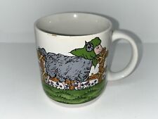 Tasse mit Schaf und drei Lämmern auf einer Wiese vor einem Zaun