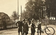 Gruppe Jungen steht mit einem Fahrrad auf einem Platz vor Schautafel Foto