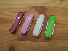 Drei Victorinox Classic (rot, rosa, weiß) + ein Victorinox Escort (hellgrün)