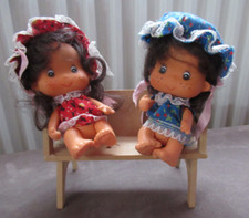 2 kleine Puppen mit Holzbank mit Mütze und Kleid