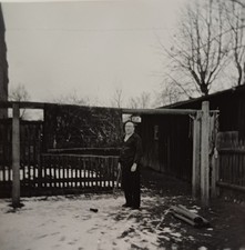 Mann steht mit Skistöcken im verschneiten Hof vor Garten Zaun Stall  Haus Foto