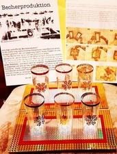 6 Becher erscheinen zwischen zwei dekorativen dünnen Platten