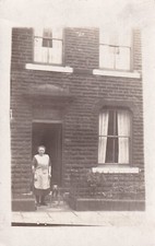 Frau in Schürze mit Hund, standen Tür Reihenhaus, Nordengland??? lw129