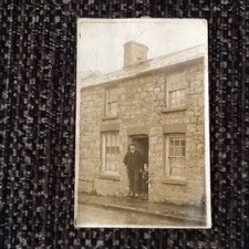 Eine frühe Fotokarte eines Mannes & Jungen in der Tür eines Reihenhauses